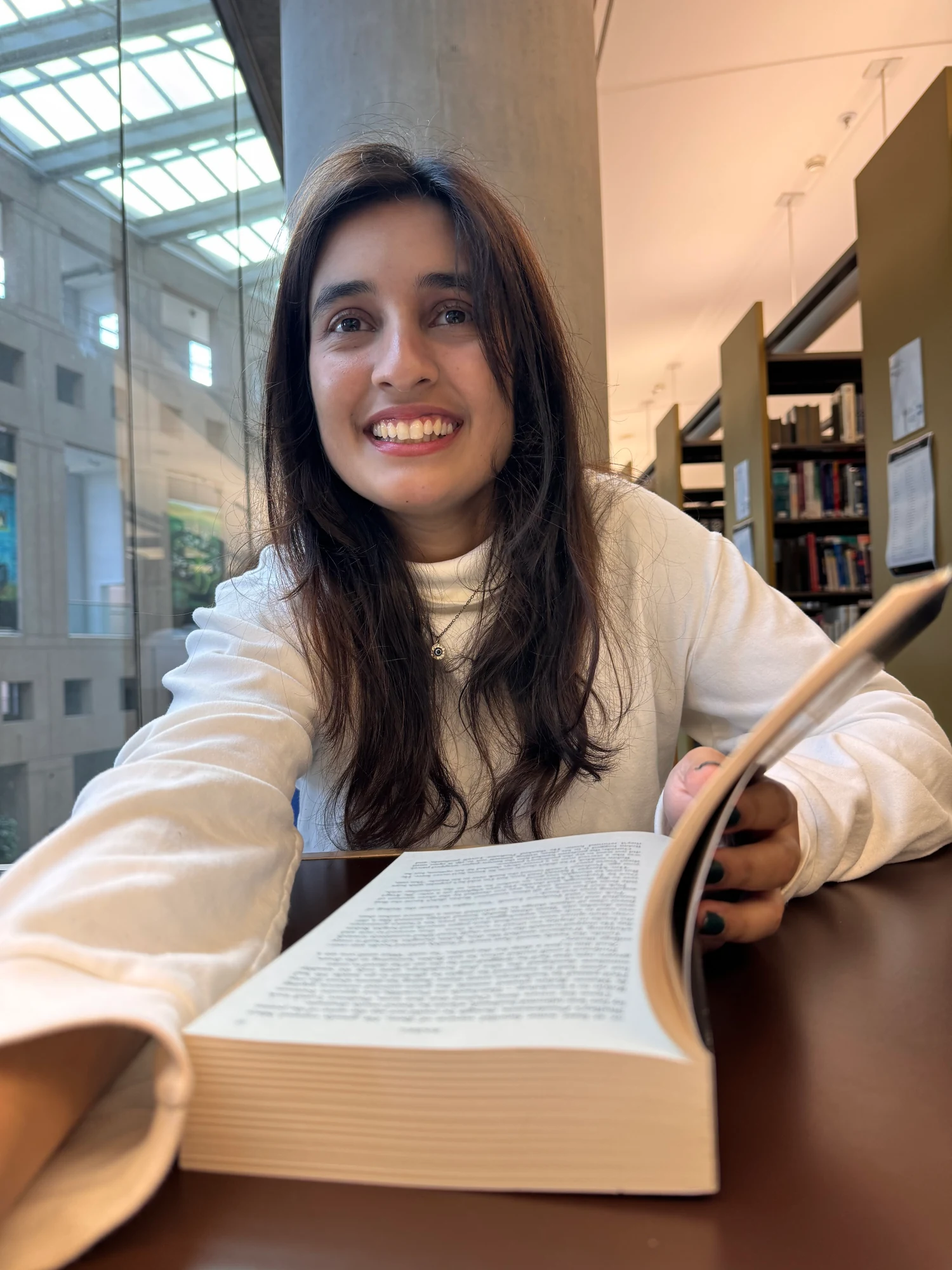 smiling with an open book at the library